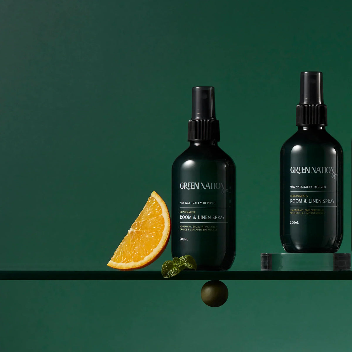 Green Nation Life room and linen spray bottles with orange slice on green background