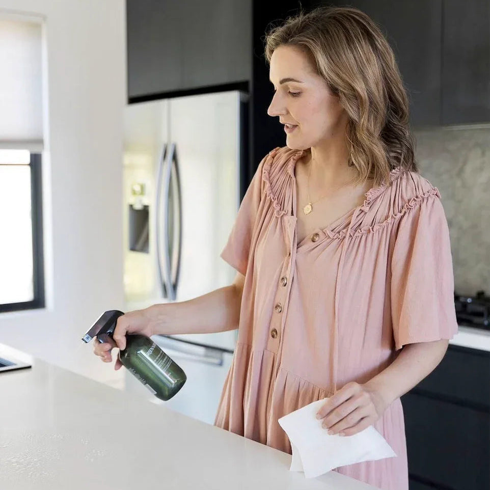 Woman cleaning kitchen countertop with spray bottle and cloth