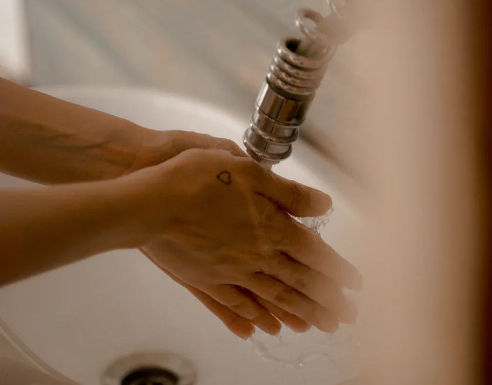 Hands washing under faucet in bathroom sink, tattoo heart on hand, hygiene concept