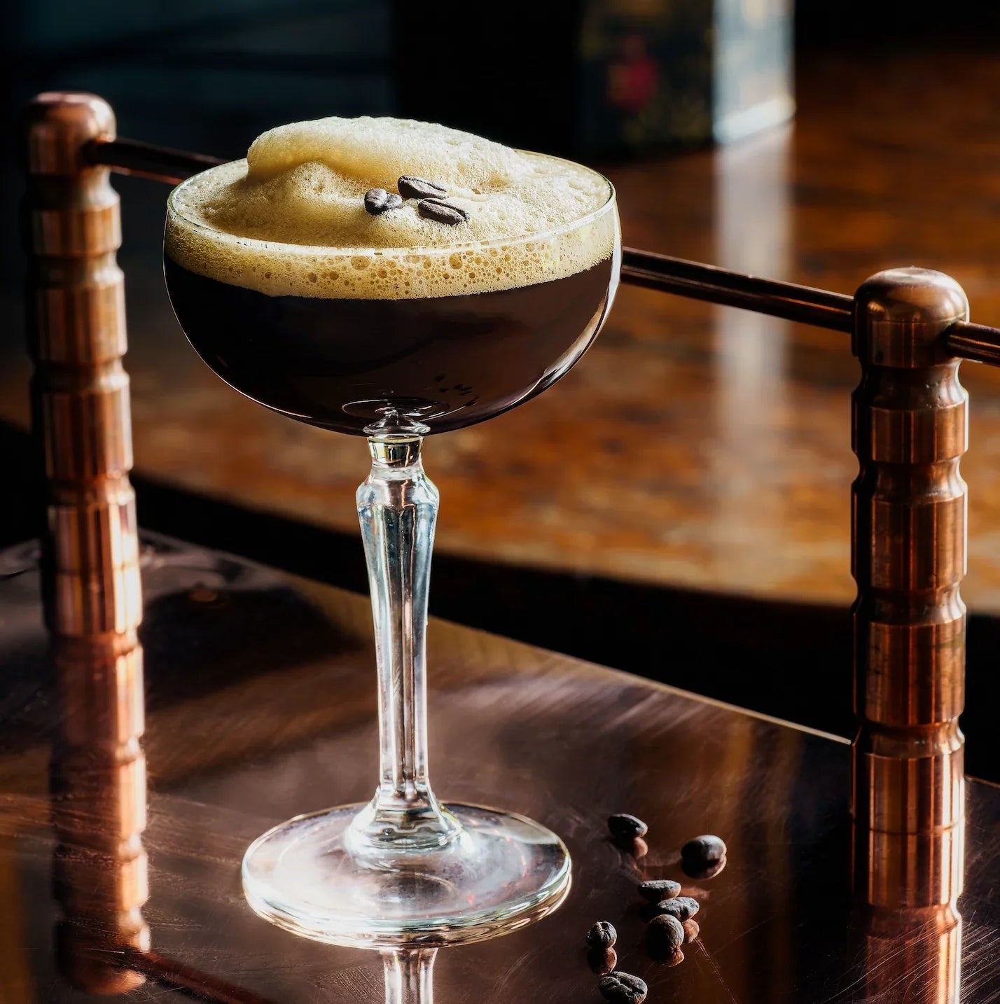 Espresso martini cocktail with foam and coffee beans in a coupe glass on a bar table