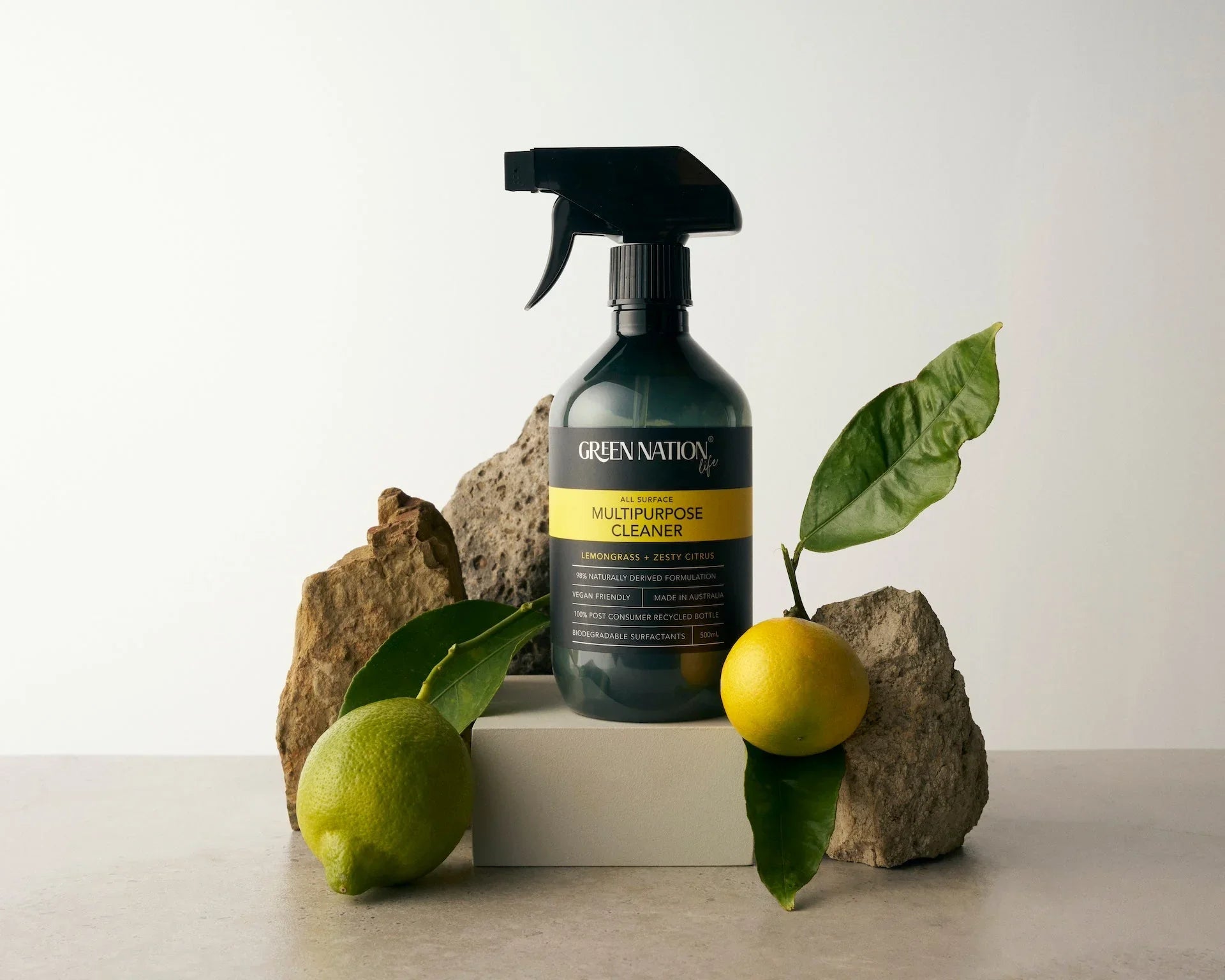 Green Nation multipurpose cleaner bottle with lemon, lime, rocks, and green leaves on gray surface